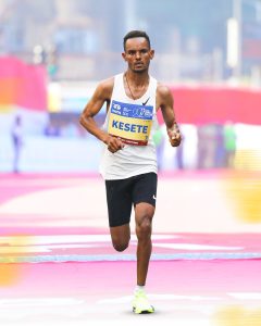 Tadu Abate Deme running mid-race at the 2026 Tata Mumbai Marathon along Marine Drive, focused and pacing himself among other elite runners.