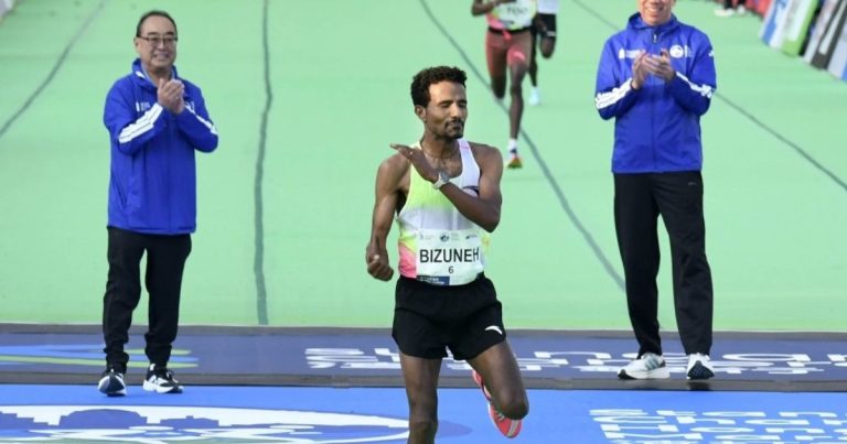 Ethiopian runner Bizueh Balachew cutting the finish line tape, arms raised in celebration, at the Hong Kong Marathon 2026